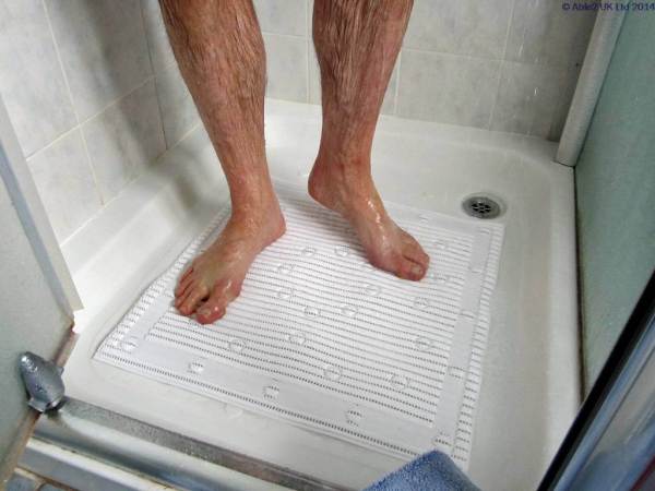 Wet feet on shower mat in accessible shower for mobility aids.