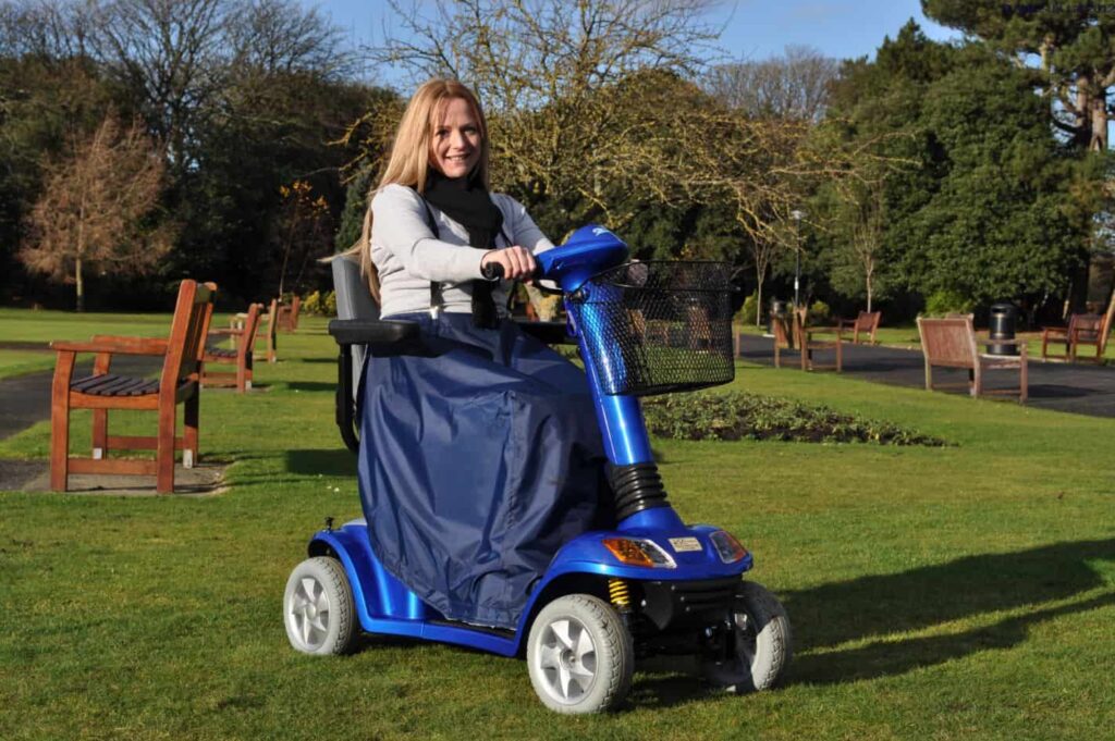 Power mobility scooter for elderly and disabled individuals in a park setting.