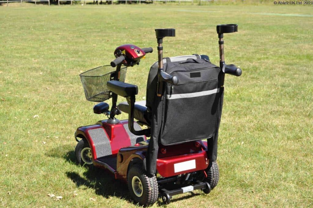 Electric mobility scooter with storage bag for elderly and disabled mobility assistance.