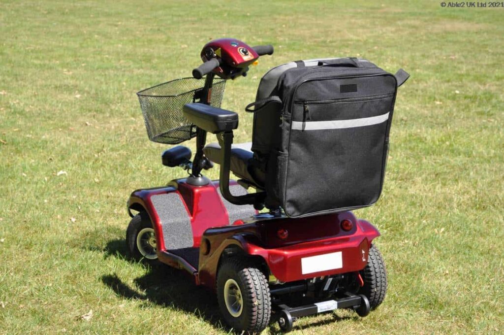Electric mobility scooter with storage bag for easy transport and improved outdoor mobility.