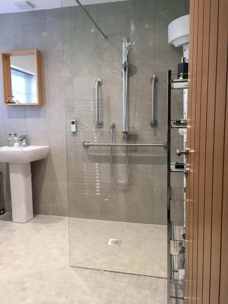 Accessible shower with grab rails and easy access features for mobility aid users.