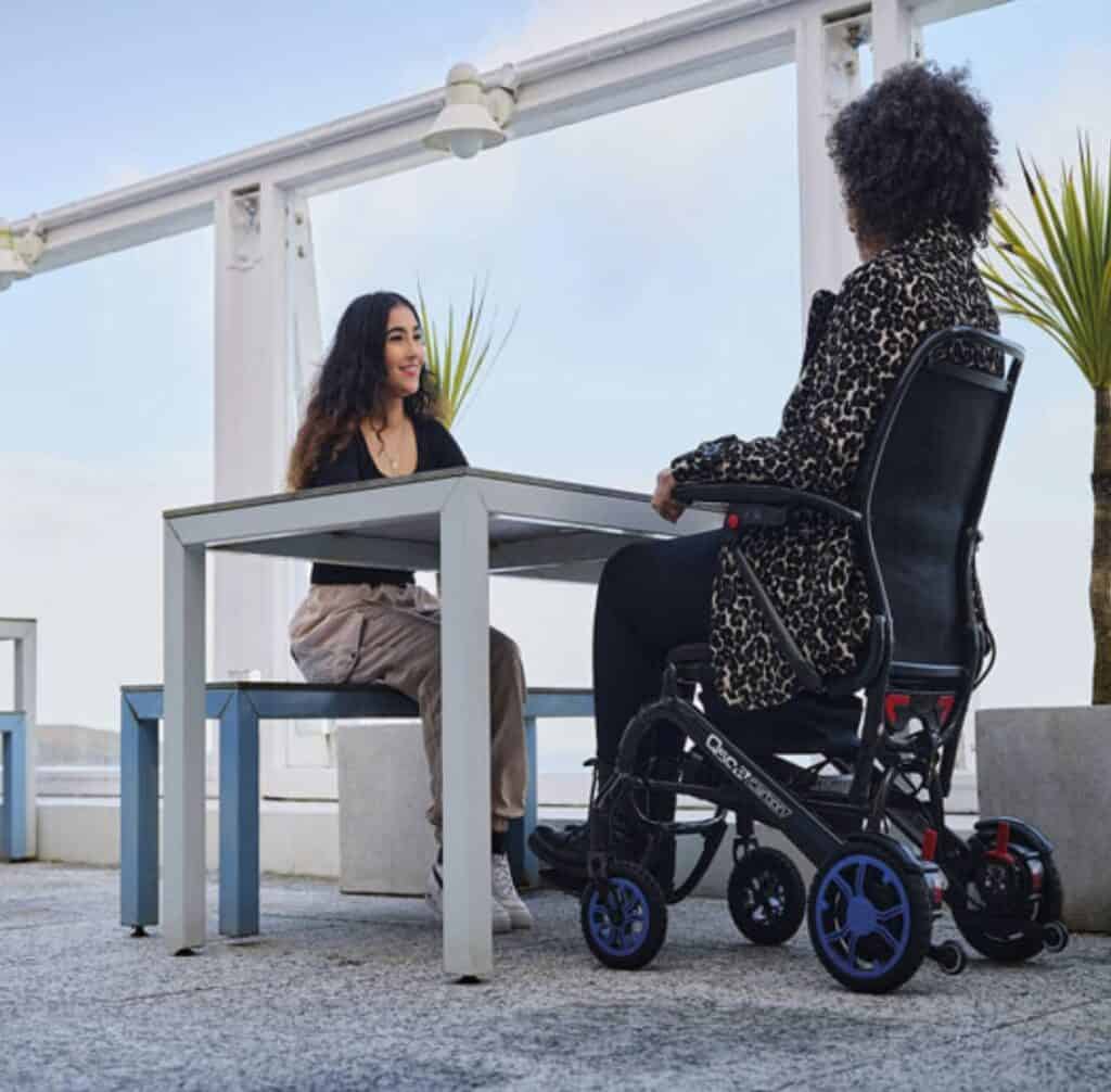 Comfortable wheelchair user enjoying outdoor mobility assistance in a modern setting.